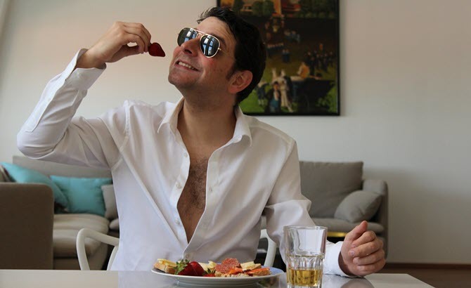 Tämä on kuva kaverista, joka syö aamiaista ja käyttää aurinkolaseja sisätiloissa
