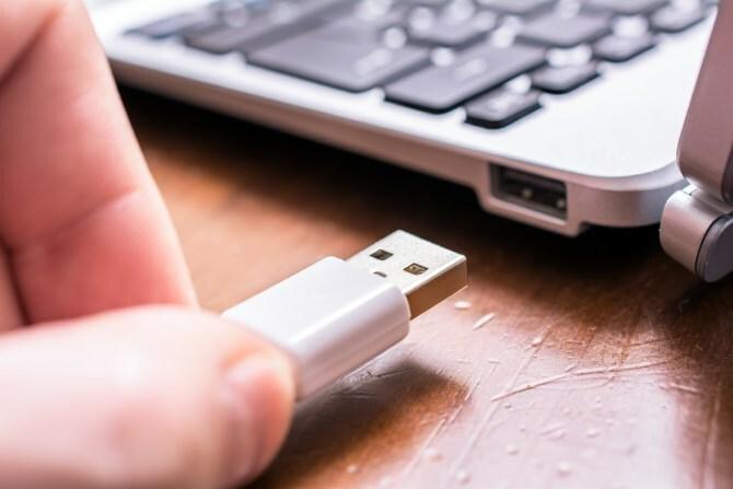 Mies irrottaa USB-laitteen tietokoneesta